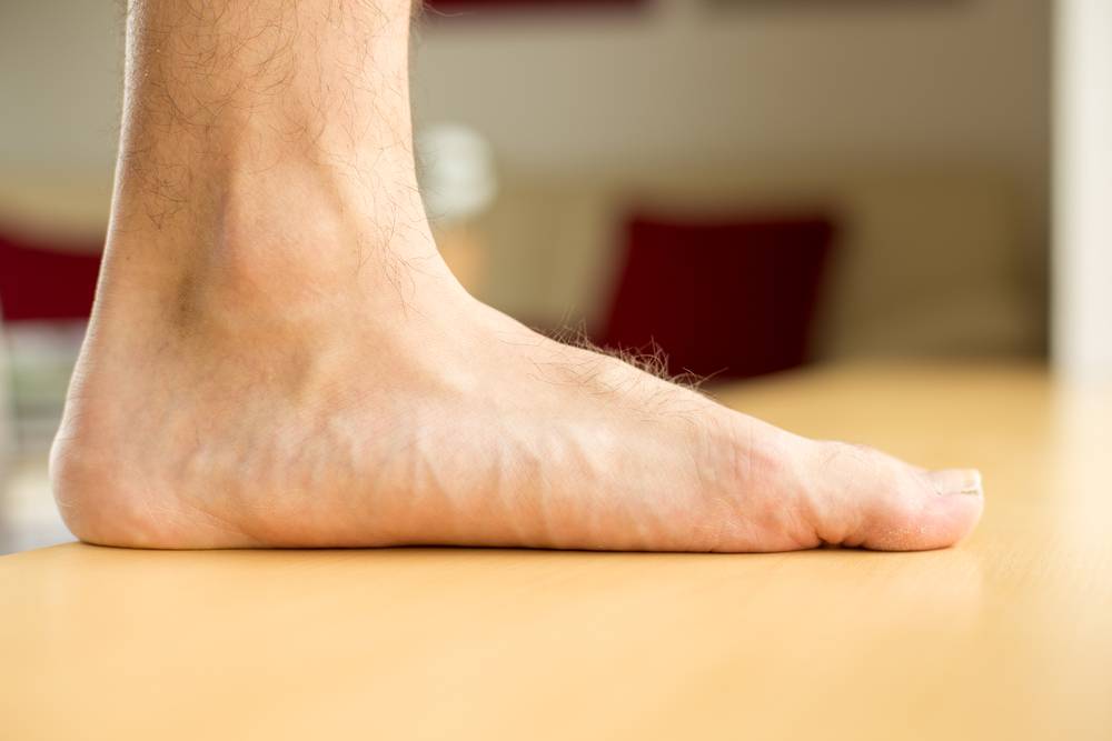pé masculino plano pisando em um chão de madeira